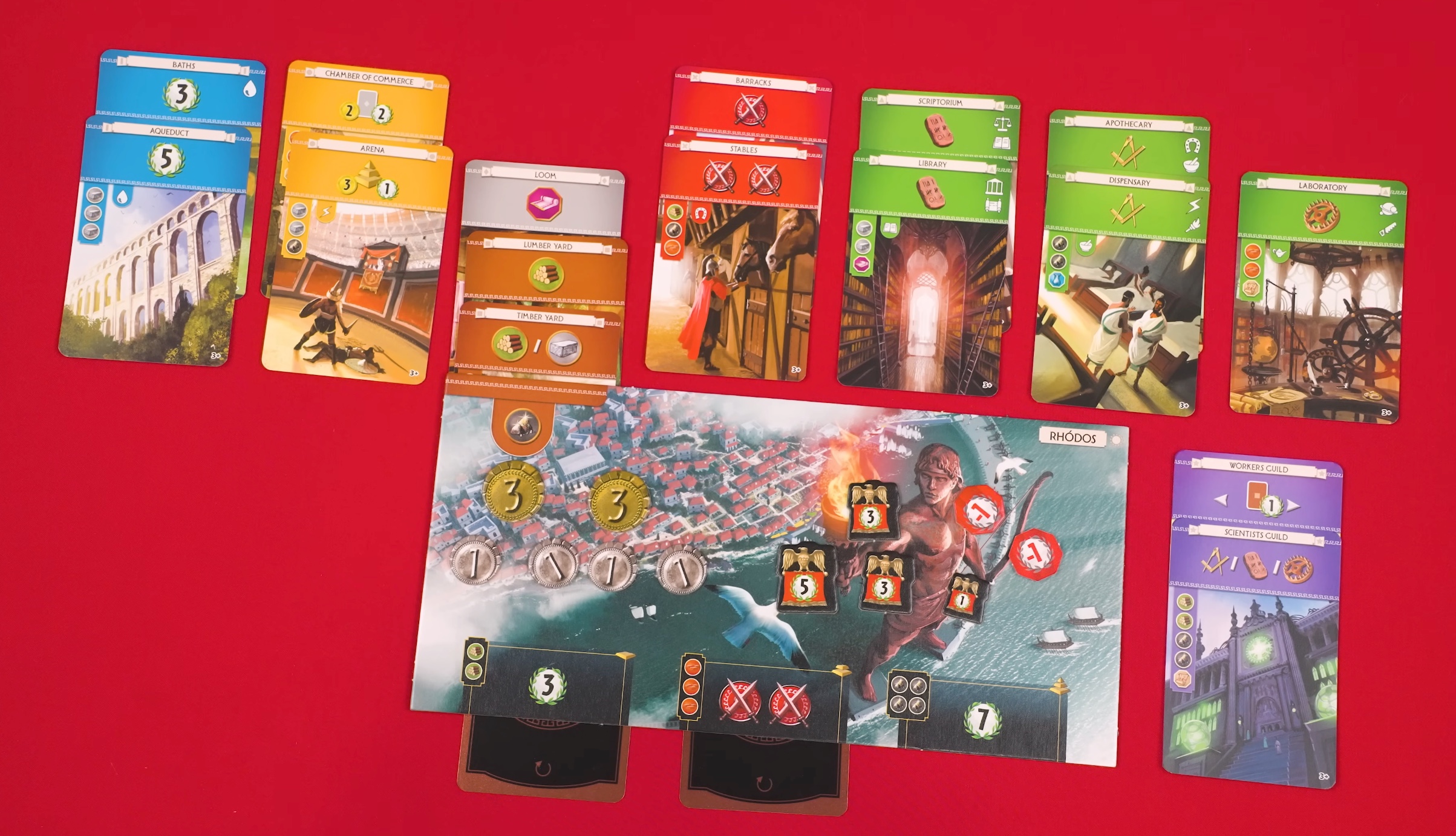 A 7 Wonders end-of-Age-II tableau for the Rhodes wonder board, showing blue civilian cards, red military cards, green science cards, a commercial card, and military tokens on the wonder board.