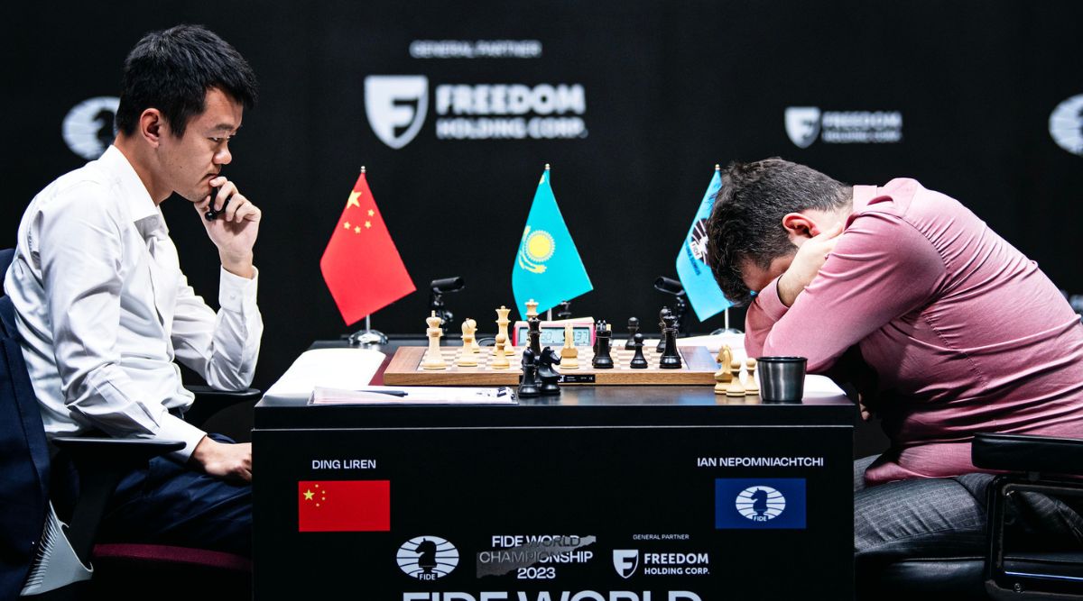 Ding Liren focused at the board while Ian Nepomniachtchi sits with his head in his hands - Game 12, 2023 FIDE World Chess Championship